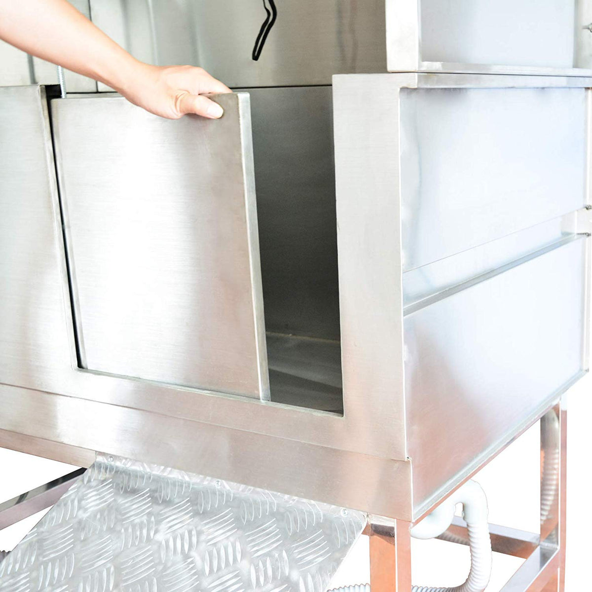 Hand opening the stainless steel dog bath's sliding access door above the ramp.
