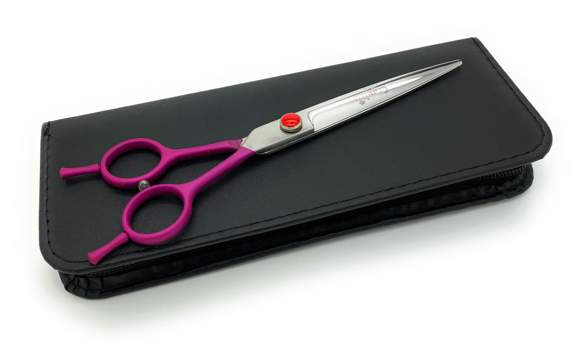 Purple-handled straight grooming scissors resting on a closed black case.